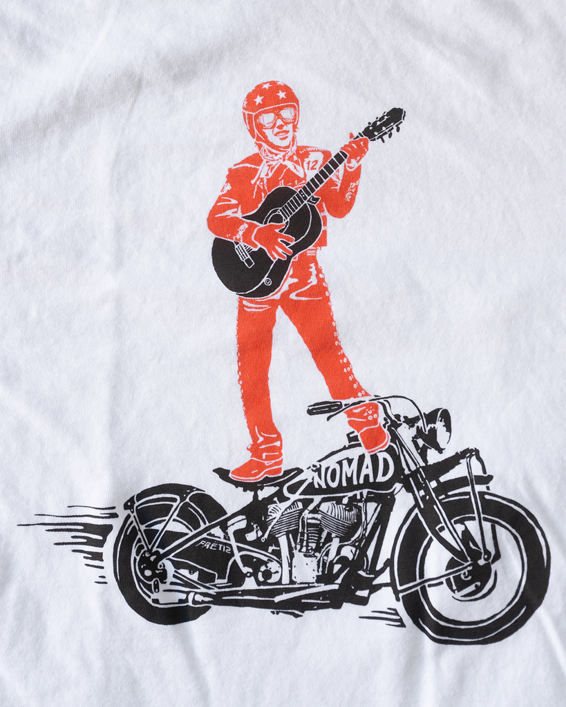 White FRET12 Mariachi Rider Tee showcasing a bold graphic of the legendary Mariachi Rider standing on a motorcycle, strumming a guitar, set against a clean, minimal backdrop.